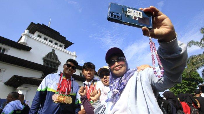 Warga berswafoto bersama atlet dayung Jawa Barat, Rudiyansyah dan Ikballana Ikhsan peraih enam medali emas dan satu perunggu pada acara penyambutan kontingen Jabar yang sudah berlaga di Pekan Olahraga Nasional (PON) XXI 2024 Aceh - Sumatera Utara, di halaman Gedung Sate, Kota Bandung, Jawa Barat, Kamis (26/9/2024).