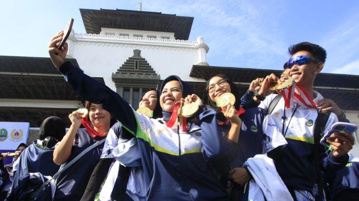 Atlet polo air berswafoto sambil memperlihatkan medali yang telah mereka raih pada acara penyambutan kontingen Jabar yang sudah berlaga di Pekan Olahraga Nasional (PON) XXI 2024 Aceh - Sumatera Utara, di halaman Gedung Sate, Kota Bandung, Jawa Barat, Kamis (26/9/2024).