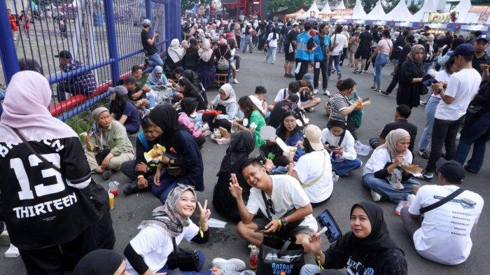 Penggemar Sheila On 7 (Sheila Gank) menikmati makan dan minum sambil lesehan di luar stadion sebelum menyaksikan konser Sheila On 7 bertajuk 