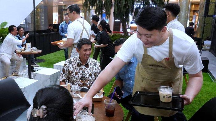 Direktur Honda Bandung Center (HBC) Iwan Tjandradinata dan Junior Area Sales Manager HBC Kevin Hartono mengantarkan kopi hasil racikannya kepada calon konsumen saat berkesempatan menjadi barista di Cafe Honda pada Grand Opening Honda Exhibition di Trans Studio Mall (TSM), Kota Bandung, Jawa Barat, Jumat (25/10/2024).