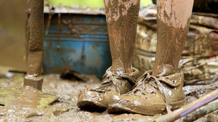 Seorang warga mengenakan sepatu yang sudah diselimuti lumpur saat beres-beres rumah pascabanjir bandang menerjang rumahnya, di Kampung Muara, Desa Banjaran Wetan, Kecamatan Banjaran, Kabupaten Bandung, Jawa Barat, Rabu (6/11/2024).