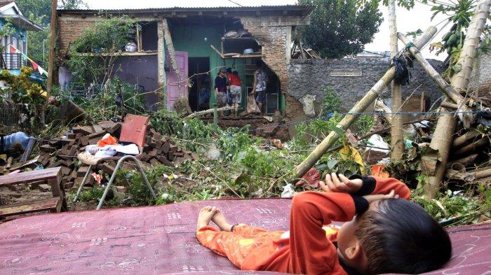 Seorang  anak kecil tidur di kasur yang disimpan di kebun dan tampak warga lainnya membereskan perabotan di ruang dapur yang dinding tembok bagian belakangnya ambruk pascabanjir bandang menerjang rumahnya, di Kampung Muara, Desa Banjaran Wetan, Kecamatan Banjaran, Kabupaten Bandung, Jawa Barat, Rabu (6/11/2024).