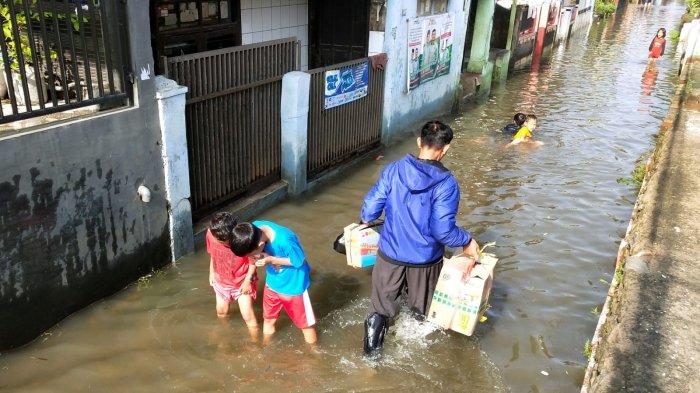 Warga melintasi jalan kampung yang tergenang banjir di Kampung Bojongasih, Desa Dayeuhkolot, Kecamatan Dayeuhkolot, Kabupaten Bandung, Jawa Barat, Selasa (12/11/2024).