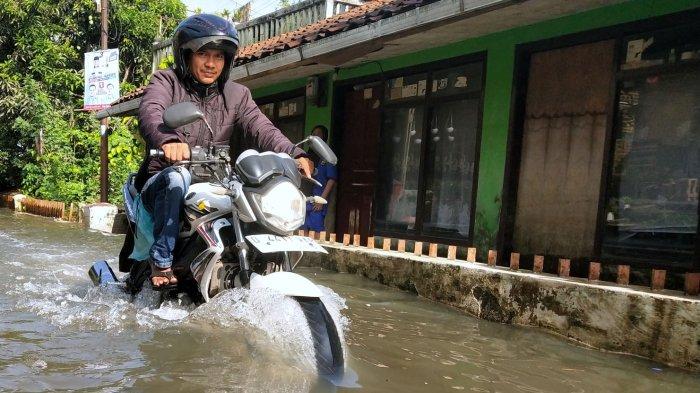 Warga melintasi jalan kampung yang tergenang banjir di Kampung Bojongasih, Desa Dayeuhkolot, Kecamatan Dayeuhkolot, Kabupaten Bandung, Jawa Barat, Selasa (12/11/2024).