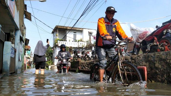Pengguna jalan melintasi jalan kampung yang tergenang banjir di Kampung Bojongasih, Desa Dayeuhkolot, Kecamatan Dayeuhkolot, Kabupaten Bandung, Jawa Barat, Selasa (12/11/2024).