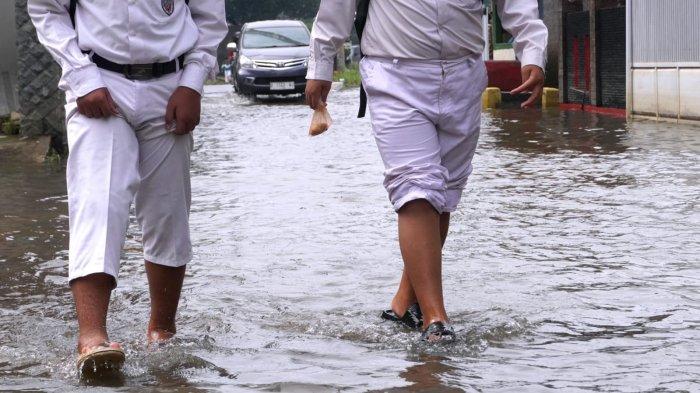 Sejumlah pelajar sekolah dasar pulang sekolah selesai mengikuti Penilaian Sumatif Akhir Semester (PSAS) Ganjil Tahun 2024 berjalan melintasi genangan banjir cileuncang di Jalan Sukabirus, Desa Citeureup, Kecamatan Dayeuhkolot, Kabupaten Bandung, Jawa Barat, Senin (2/12/2024).