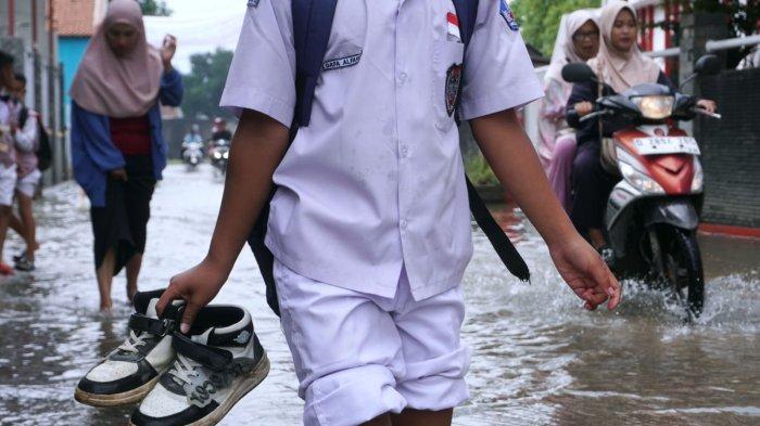 Sejumlah pelajar sekolah dasar pulang sekolah selesai mengikuti Penilaian Sumatif Akhir Semester (PSAS) Ganjil Tahun 2024 berjalan melintasi genangan banjir cileuncang di Jalan Sukabirus, Desa Citeureup, Kecamatan Dayeuhkolot, Kabupaten Bandung, Jawa Barat, Senin (2/12/2024).