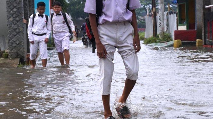 Sejumlah pelajar sekolah dasar pulang sekolah selesai mengikuti Penilaian Sumatif Akhir Semester (PSAS) Ganjil Tahun 2024 berjalan melintasi genangan banjir cileuncang di Jalan Sukabirus, Desa Citeureup, Kecamatan Dayeuhkolot, Kabupaten Bandung, Jawa Barat, Senin (2/12/2024).