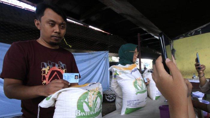 Petugas mendokumentasikan warga penerima manfaat saat penyaluran program Bantuan Pangan Cadangan Beras Pemerintah (CBP) Tahap III Tahun 2024 di bawah flyover Mochtar Kusumaatmadja (Pasupati), Kelurahan Tamansari, Kecamatan Bandung Wetan, Kota Bandung, Jawa Barat, Selasa (11/12/2024).