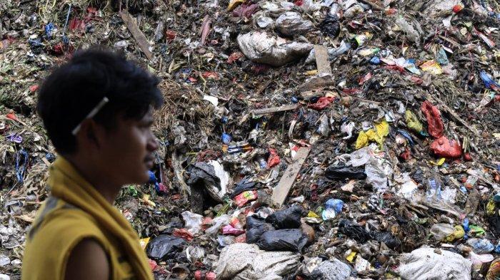 Seorang pekerja pasar meintasi hamparan sampah yang menggunung di area depan Pasar Induk Caringin, Jalan Soekarno Hatta, Kota Bandung, Senin (16/12/2024).