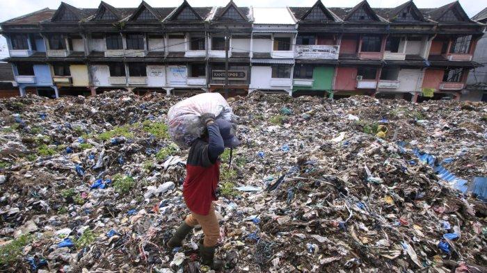 Seorang petugas membawa sampah berjalan di atas hamparan sampah yang menggunung di area depan Pasar Induk Caringin, Jalan Soekarno Hatta, Kota Bandung, Senin (16/12/2024).