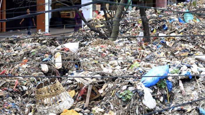 Seorang warga melintas di samping hamparan sampah yang menggunung di area depan Pasar Induk Caringin, Jalan Soekarno Hatta, Kota Bandung, Senin (16/12/2024).