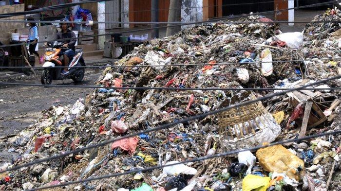 Pengendara sepeda motor melintas di samping hamparan sampah yang menggunung di area depan Pasar Induk Caringin, Jalan Soekarno Hatta, Kota Bandung, Senin (16/12/2024).
