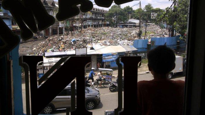 Seorang warga melihat dari jauh hamparan sampah yang menggunung di area depan Pasar Induk Caringin, Jalan Soekarno Hatta, Kota Bandung, Senin (16/12/2024).