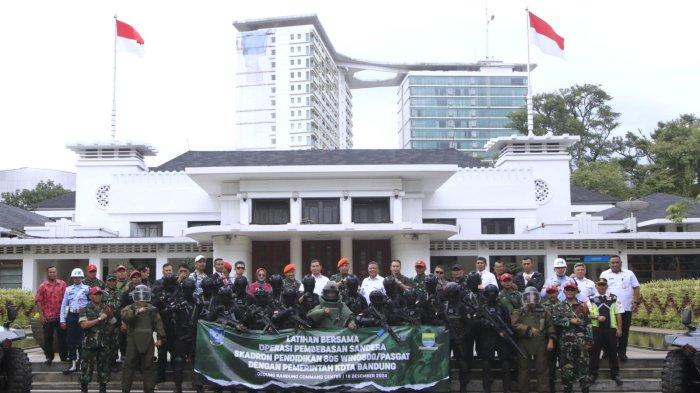 Komandan Wingdik 800/Pasgat, Kolonel Pas Harry Nugroho dan Pj Sekretaris Daerah Kota Bandung, Dharmawan berfoto bersama para siswa Kursus Bravo 90 Angkatan ke-18 Komando Pasukan Gerak Cepat (Kopasgat) TNI Angkatan Udara yang telah melaksanakan Latihan Praktis (Lattis) Operasi Pembebasan Sandera dan Penjinakan Bom di Gedung Bandung Command Center (BCC), Balai Kota Bandung, Jalan Wastukencana, Kota Bandung, Jawa Barat, Rabu (18/12/2024).