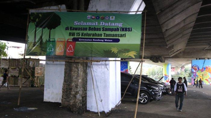 Warga melintasi baliho bertuliskan Kawasan Bebas Sampah di lahan yang sudah mulai sedikit tertata di kolong Flyover Mochtar Kusumaatmadja (Pasupati), Kelurahan Tamansari, Kecamatan Bandung Wetan, Kota Bandung, Jumat (20/12/2024).