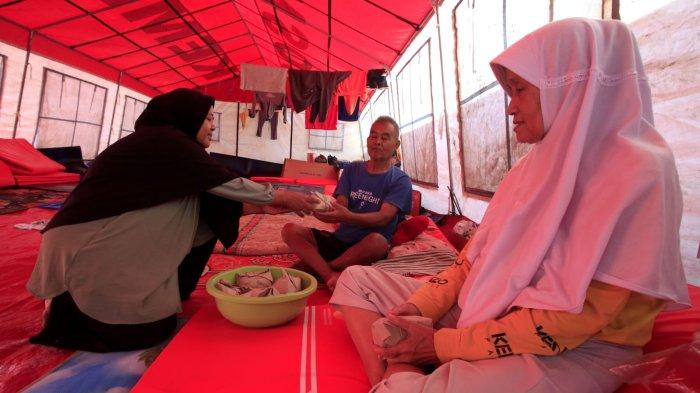 Warga terdampak banjir menerima nasi bungkus di tenda pengungsian di Taman Air, Kampung Cijagra, RW 10, Desa/Kecamatan Bojongsoang, Kabupaten Bandung, Jawa Barat, Jumat (29/11/2024).