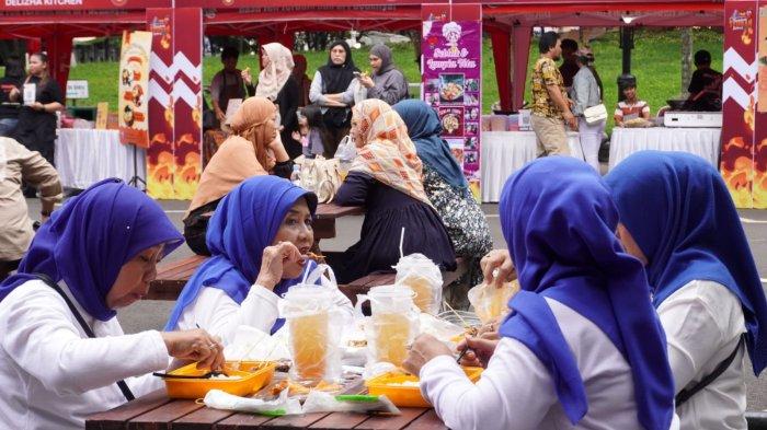 Pengunjung menikmati jajanan yang baru dibeli pada gelaran Bandung Seuhah Festival 2024, di area parkir Balai Kota Bandung, Jalan Wastukencana, Kota Bandung, Jawa Barat, Sabtu (30/11/2024).