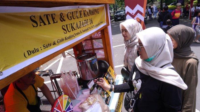 Pengunjung membeli jajanan pada gelaran Bandung Seuhah Festival 2024, di area parkir Balai Kota Bandung, Jalan Wastukencana, Kota Bandung, Jawa Barat, Sabtu (30/11/2024).