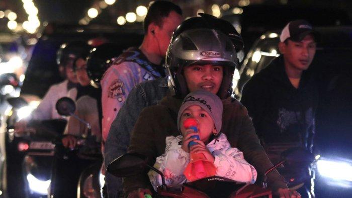 Seorang anak bersama orang tuanya akan merayakan tahun baru 2025 meniup terompet saat berkendaraan melintas di Jalan Asia Afrika, Kota Bandung, Jawa Barat, Selasa (31/12/2024) malam.