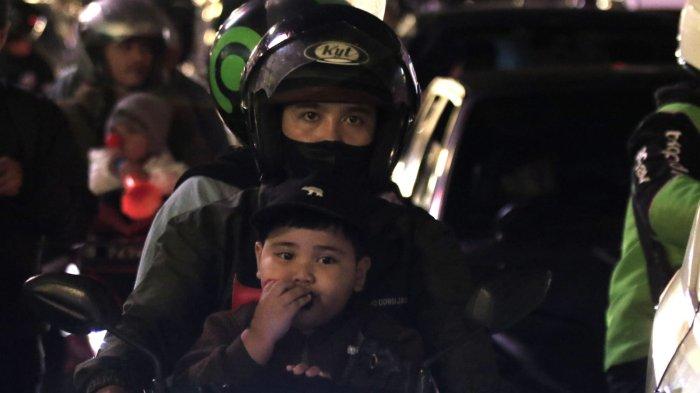 Seorang anak bersama orang tuanya akan merayakan tahun baru 2025 meniup terompet saat berkendaraan melintas di Jalan Asia Afrika, Kota Bandung, Jawa Barat, Selasa (31/12/2024) malam.