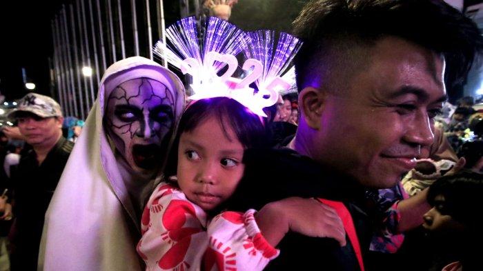 Seorang anak kecil benbando 2025 berfoto bersama manusia berkostum hantu saat merayakan tahun baru 2025 di kawasan Jalan Asia Afrika, Kota Bandung, Jawa Barat, Selasa (31/12/2024) malam.