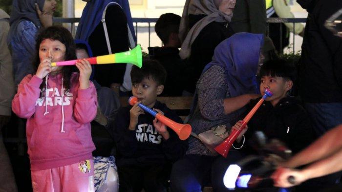 Tiga anak kecil bersama orang tuanya meniup terompet saat merayakan tahun baru 2025 di kawasan Jalan Braga, Kota Bandung, Jawa Barat, Selasa (31/12/2024) malam.