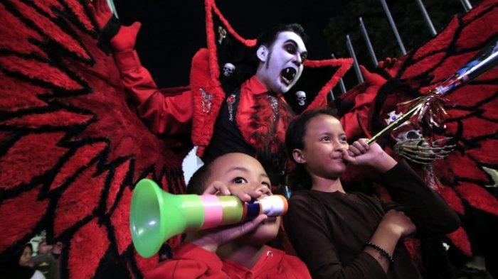 Dua anak kecil berfoto bersama manusia berkostum hantu sambil meniup terompet saat merayakan tahun baru 2025 di kawasan Jalan Asia Afrika, Kota Bandung, Jawa Barat, Selasa (31/12/2024) malam.
