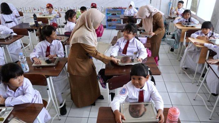 Guru membagikan makanan sehat bergizi dalam program Makan Bergizi Gratis (MBG) hari pertama, di SD Angkasa, Lanud Husein Sastranegara, Kota Bandung, Jawa Barat, Senin (6/1/2025).