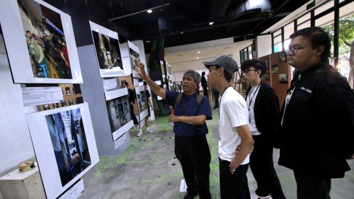 Dosen Fotografi Universitas Pasundan (Unpas), Sjuaibun iljas (kiri) menjelaskan salah satu foto yang dipamerkan kepada pengunjung pada gelaran Pameran Foto Urban Visual: Kampung Braga di Gedung Bandung Creative Hub, Jalan Laswi, Kota Bandung, Jawa Barat, Selasa (21/1/2025).