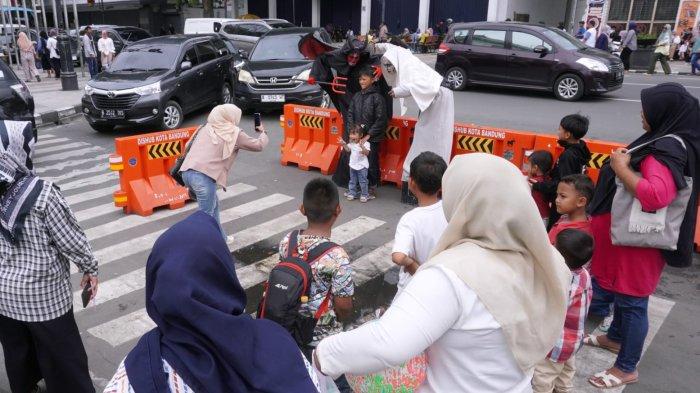 Wisatawan berfoto bersama orang berkostum hantu saat mengisi liburan di Jalan Asia Afrika, Kota Bandung, Jawa Barat, Senin (27/1/2025).