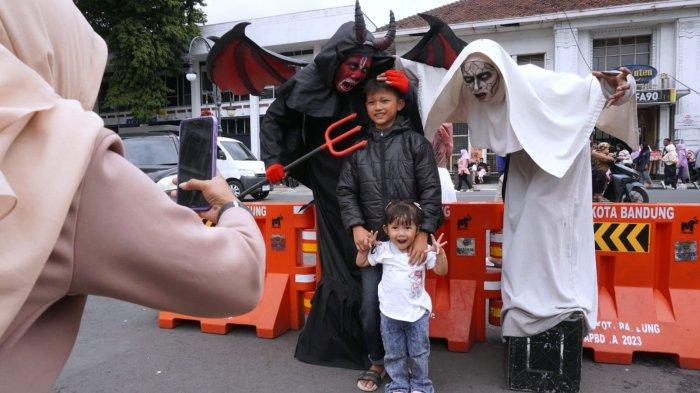 Wisatawan berfoto bersama orang berkostum hantu saat mengisi liburan di Jalan Asia Afrika, Kota Bandung, Jawa Barat, Senin (27/1/2025).