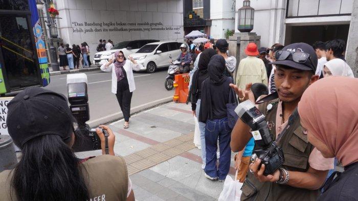 Wisatawan berfoto di bawah Jembatan Penyeberangan Orang (JPO) dengan latar belakang tulisan ungkapan Pidi Baiq 