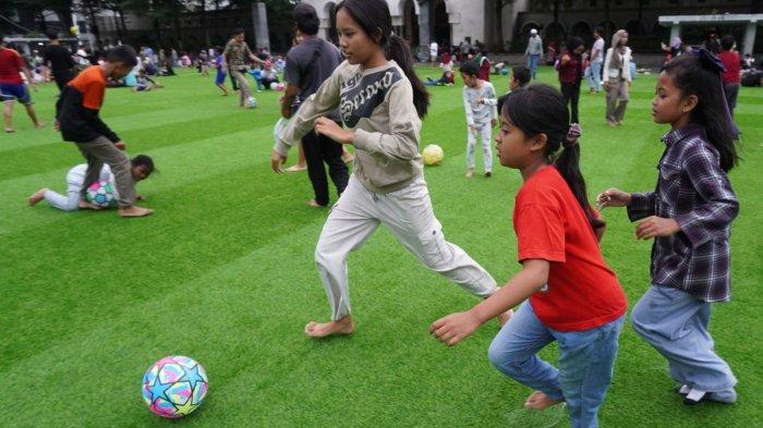 Sejumlah anak bermain bola saat mengisi liburan di lapangan rumput sintetis taman Alun-Alun Kota Bandung, Jawa Barat, Selasa (28/1/2025).