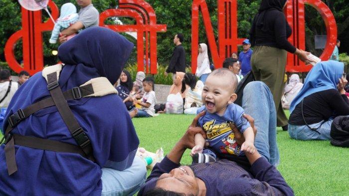 Orang tua bermain bersama anaknya saat mengisi liburan di lapangan rumput sintetis taman Alun-Alun Kota Bandung, Jawa Barat, Selasa (28/1/2025).
