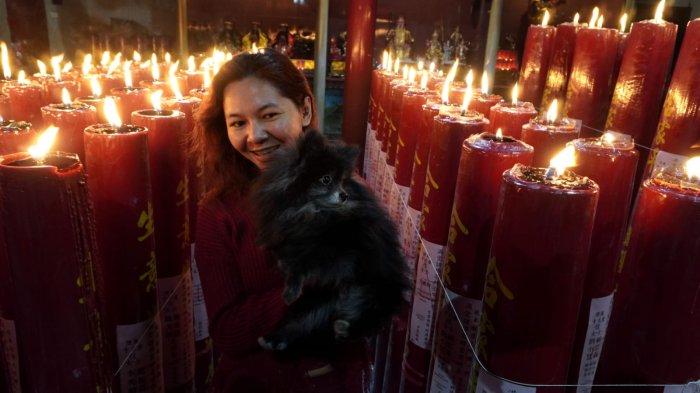 Warga keturunan Tionghoa berjalan diantara lilin-lilin yang menyala selesai melakukan sembahyang malam di Vihara Dharma Ramsi, Gang Ibu Aisah, Jalan Cibadak, Kota Bandung, Jawa Barat, Selasa (28/1/2025).