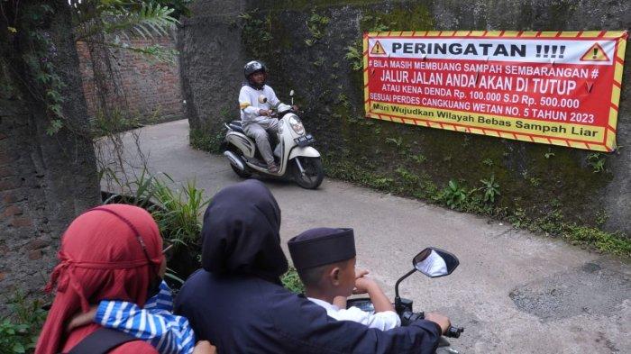 Pengendara bermotor melintasi spanduk bertuliskan himbauan untuk tidak membuang sampah sembarangan di Jalan Citra, Desa Cangkuang Wetan, Kecamatan Dayeuhkolot, Kabupaten Bandung, Jawa Barat, Selasa (18/2/2025).