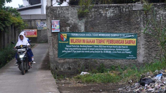 Pengendara bermotor melintasi spanduk bertuliskan himbauan untuk tidak membuang sampah sembarangan di Jalan Citra, Desa Cangkuang Wetan, Kecamatan Dayeuhkolot, Kabupaten Bandung, Jawa Barat, Selasa (18/2/2025).