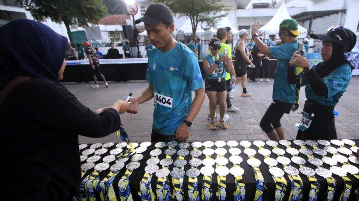 Peserta mengambil medali setelah masuk garis finish dalam ajang PLN Jabar Smile Run 2025, di Jalan Ir Sukarno, kawasan Gedung Merdeka, Kota Bandung, Jawa Barat, Minggu (23/2/2025).
