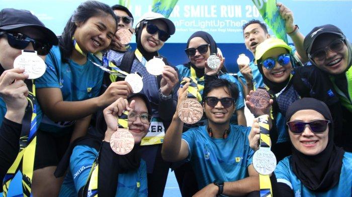 Sejumlah peserta memegang medali setelah masuk garis finish dalam ajang PLN Jabar Smile Run 2025, di Jalan Ir Sukarno, kawasan Gedung Merdeka, Kota Bandung, Jawa Barat, Minggu (23/2/2025).