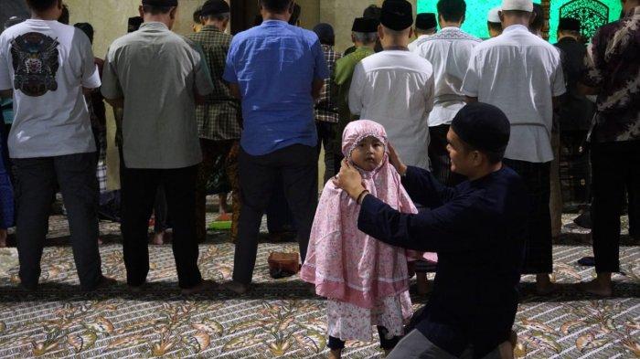 Seorang bapak merapikan mukena anak perempuannya saat akan melaksanakan salat tarawih perdana di Masjid Raya Bandung Provinsi Jawa Barat, Alun-Alun Kota Bandung, Jawa Barat, Jumat (28/2/2025).