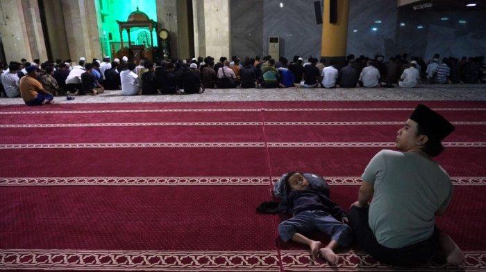 Seorang anak kecil tertidur saat orang tuanya melaksanakan salat tarawih perdana di Masjid Raya Bandung Provinsi Jawa Barat, Alun-Alun Kota Bandung, Jawa Barat, Jumat (28/2/2025).