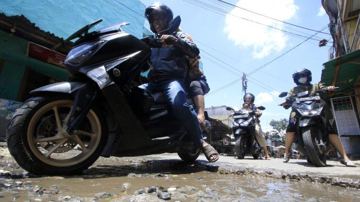 Kendaraan bermotor melintasi permukaan jalan rusak yang digenangi air di Jalan Ciroyom Barat, Kelurahan Ciroyom, Kecamatan Andir, Kota Bandung, Jawa Barat, Selasa (11/3/2025).