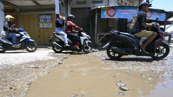 Sepeda motor melintasi permukaan jalan rusak yang digenangi air di Jalan Ciroyom Barat, Kelurahan Ciroyom, Kecamatan Andir, Kota Bandung, Jawa Barat, Selasa (11/3/2025).