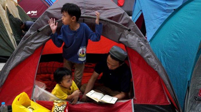 Umat Islam membaca Alquran di dalam tenda ditemani anaknya saat mengikuti itikaf di Masjid Habiburrahman PTDI, Jalan Pajajaran, Kota Bandung, Jawa Barat, Jumat (21/3/2025) dinihari.