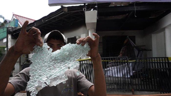 Seorang pekerja memperlihatkan pecahan kaca di depan Kantor Hana Bank yang hangus terbakar di persimpangan Jalan Ir H Djuanda - Jalan Diponegoro, Dago, Kota Bandung, Jawa Barat, Sabtu (21/3/2025).