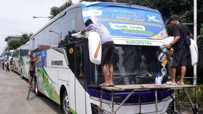 Sejumlah pekerja memasang stiker Mudik Gratis Bersama Pemprov Jabar dan Jasa Raharja pada bus pariwisata di Pool Bus Pariwisata Suryaputra (SPA), Jalan Leuwipanjang, Kota Bandung, Jawa Barat, Selasa (25/3/2025).