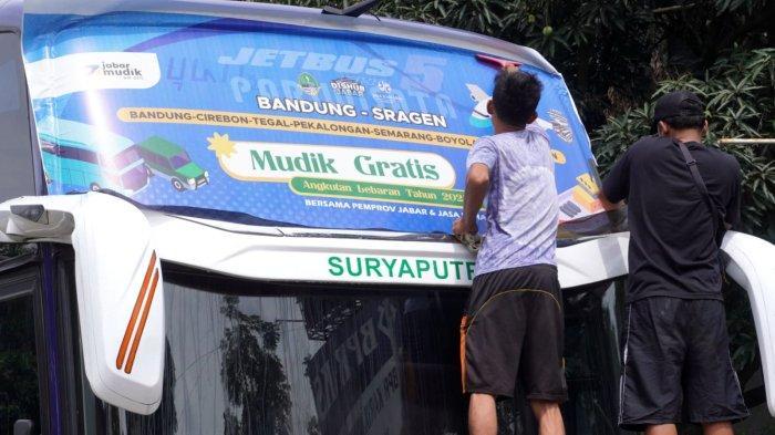 Sejumlah pekerja memasang stiker Mudik Gratis Bersama Pemprov Jabar dan Jasa Raharja pada bus pariwisata di Pool Bus Pariwisata Suryaputra (SPA), Jalan Leuwipanjang, Kota Bandung, Jawa Barat, Selasa (25/3/2025).