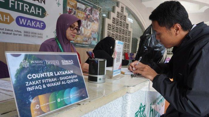 Warga membayar zakat fitrah di Counter Penerimaan Zakat Maal, Fitrah, Infaq, Shadaqah, dan Wakaf Alquran, di Masjid Pusdai Jabar, Jalan Diponegoro, Kota Bandung, Jawa Barat, Rabu (26/3/2025).