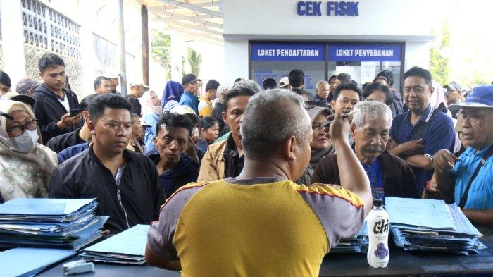 Warga Warga yang akan membayar pajak kendaraan bermotor (PKB) menyaksikan petugas mengecek berkas kendaraan roda dua yang baru selesai cek fisik di halaman Kantor Samsat Soreang, Jalan Raya Gading Tutuka, Cingcin, Kabupaten Bandung, Jawa Barat, Rabu (9/4/2025).